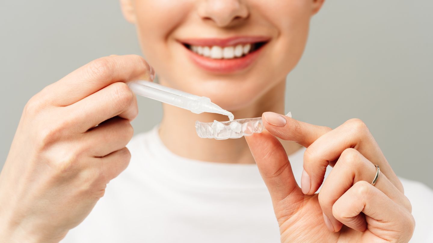 A patient applying KöR teeth whitening gel